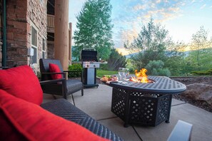 An outdoor patio with a round table, chairs, and a grill.