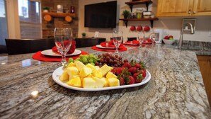 Un'isola cucina in marmo con vassoi di frutta e bicchieri da vino.
