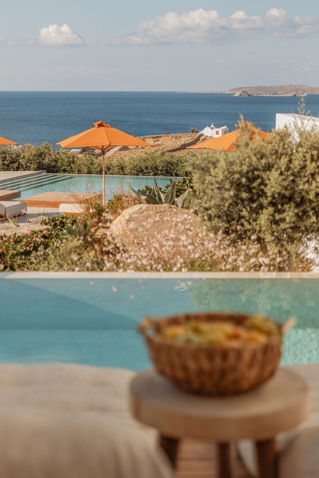 A poolside view with a clear view of the sea and distant hills.
