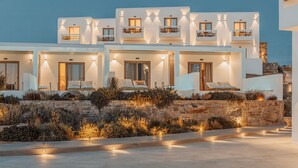 Un hotel moderno de varios pisos, con balcones, mobiliario exterior y un jardín ajardinado.