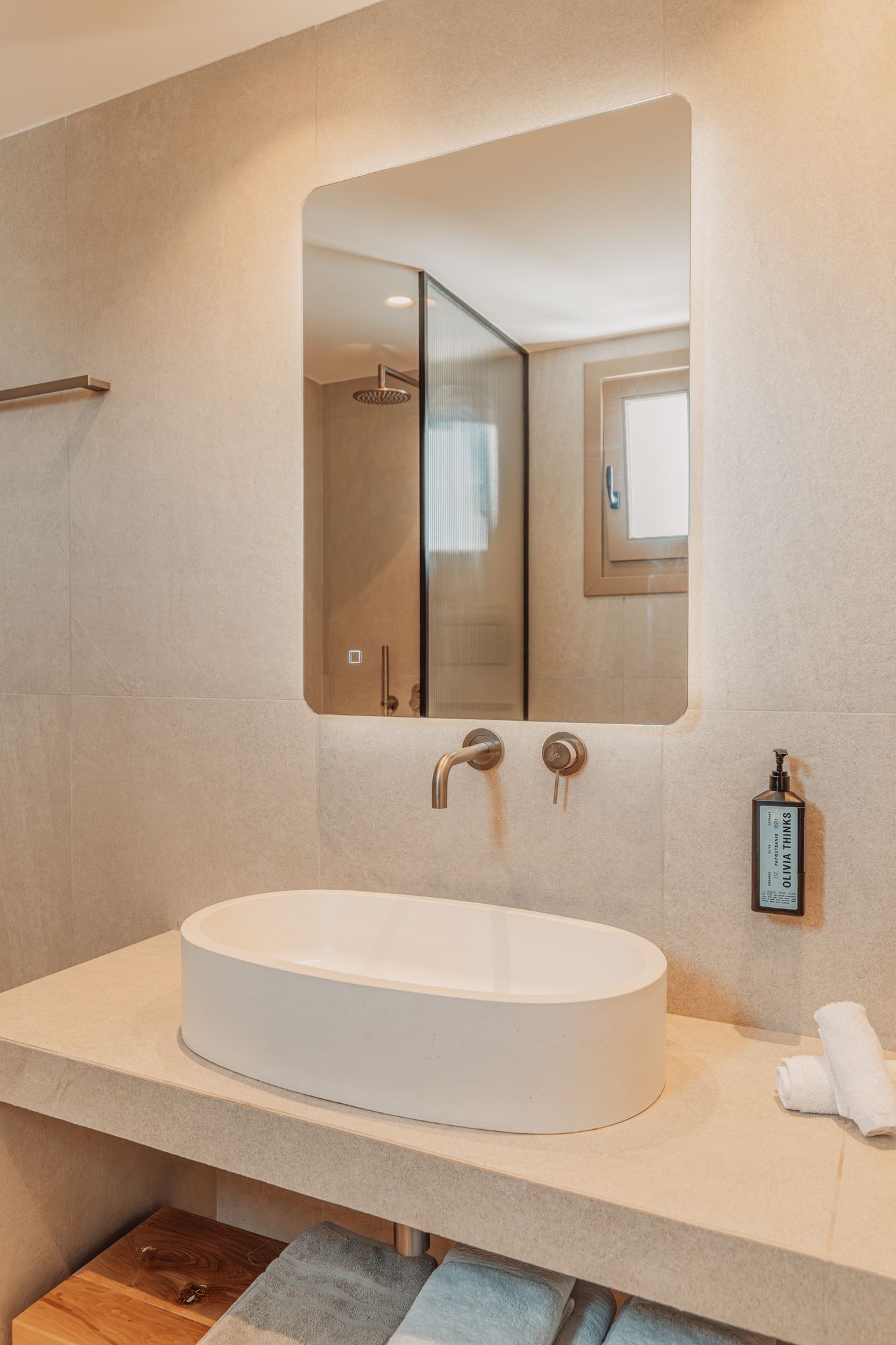 Un baño moderno con un lavamanos ovalado grande, un espejo y un perchero para toallas.