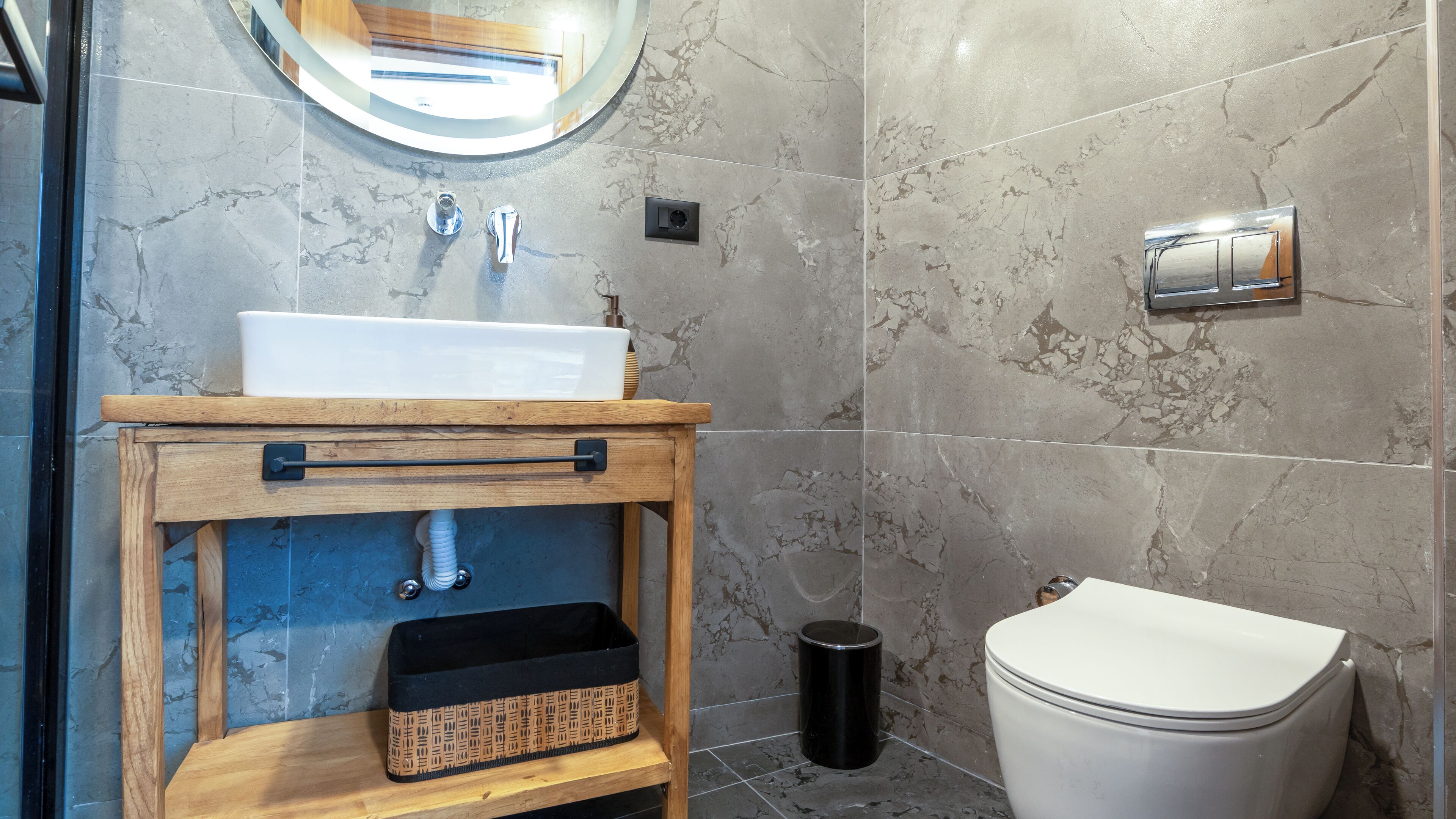 Une salle de bain avec un meuble-lavabo en bois, un lavabo blanc et des toilettes.
