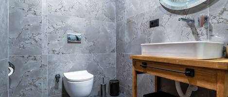 Un baño con inodoro, lavabo, espejo y paredes de mármol.