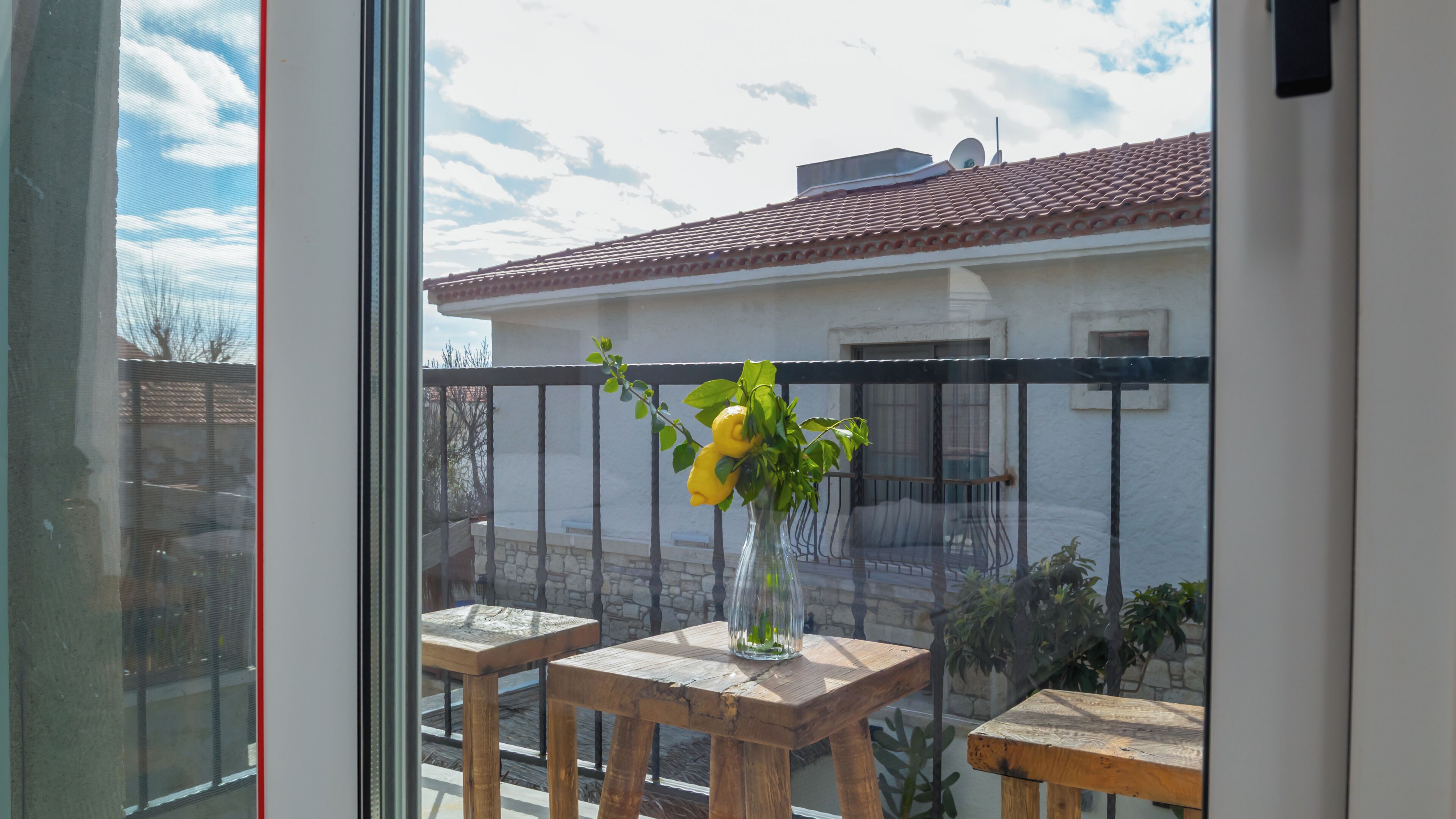 Ein Balkon mit Holztisch und einer Vase mit gelben Blumen.