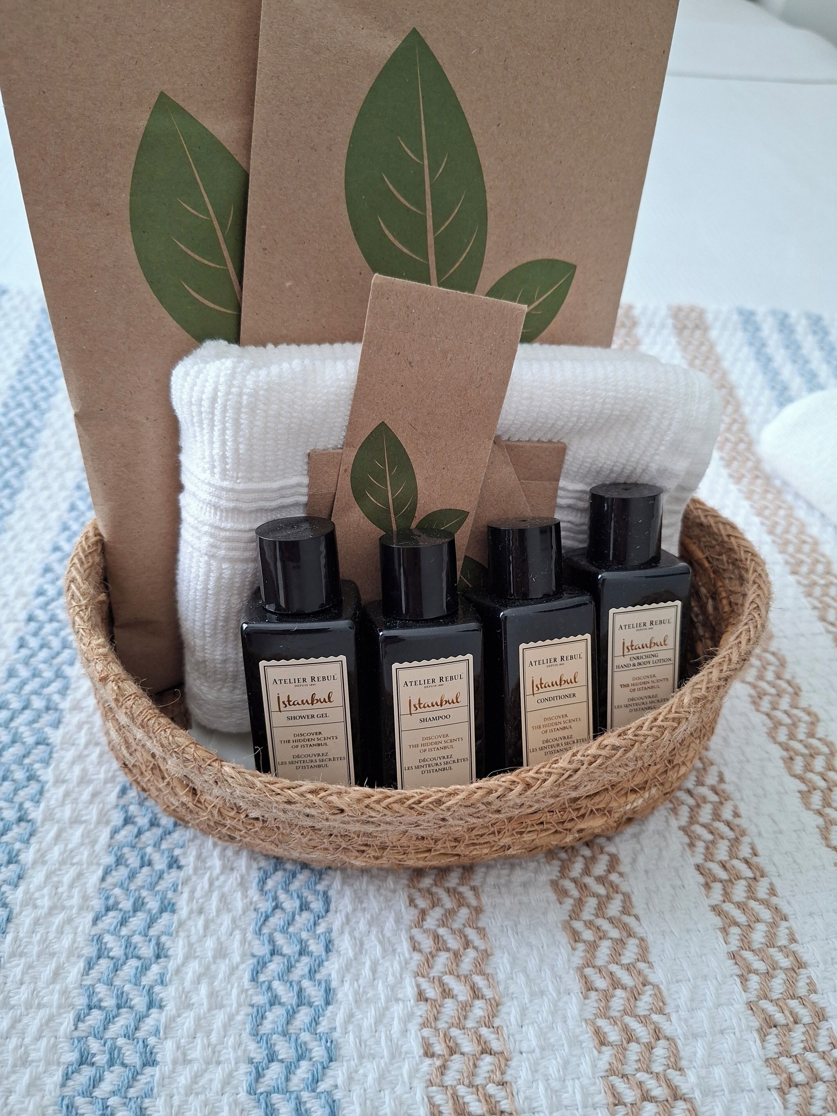 A woven basket containing bottles of Istanbul shower gel, shampoo, and hand & body lotion.