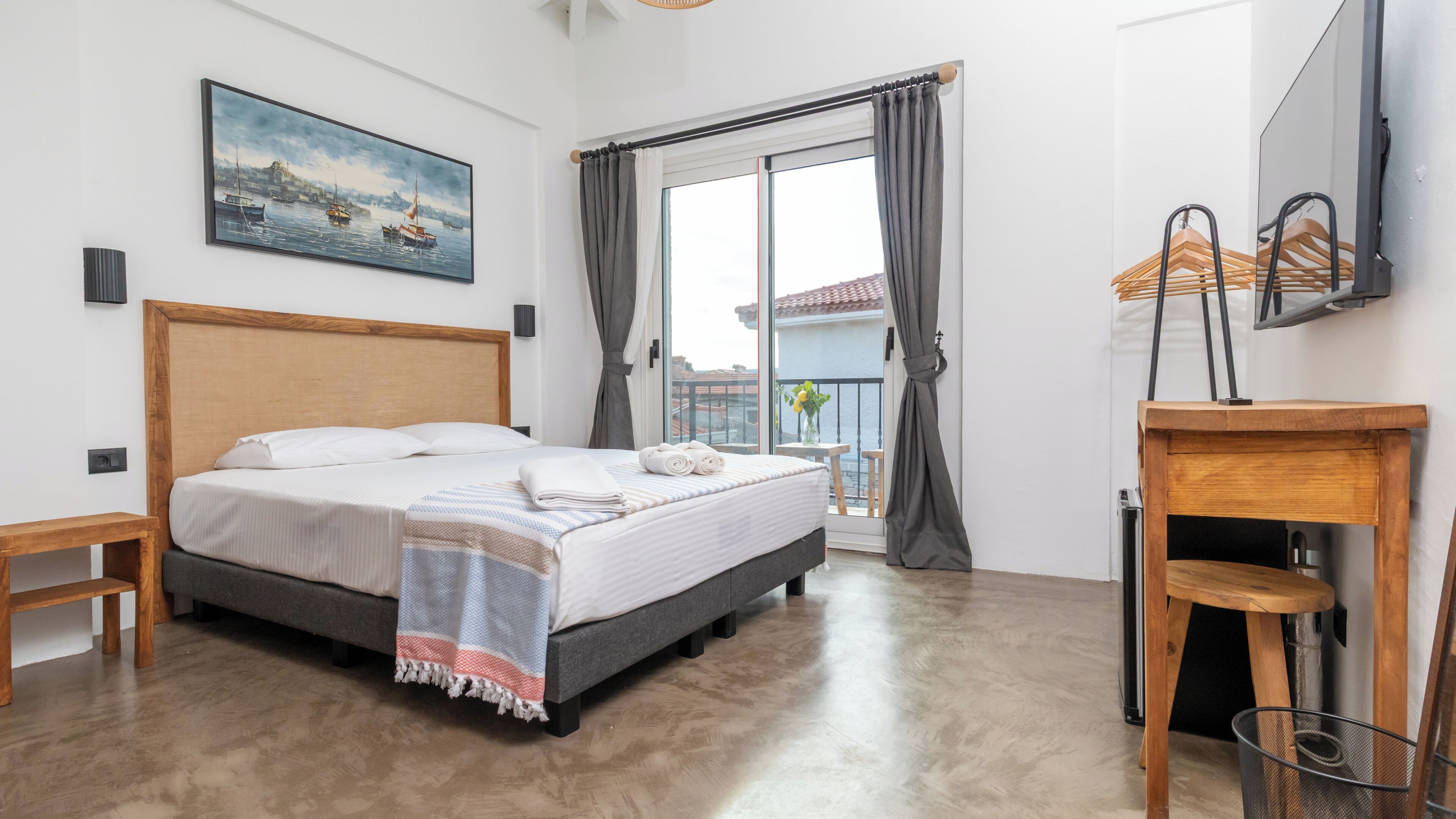 A bedroom with a bed, a painting, a window with curtains, a balcony, and a mirror.