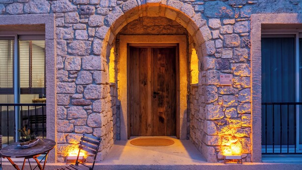 Un edificio de piedra con una puerta de madera, un banco y una pequeña mesa en el exterior.