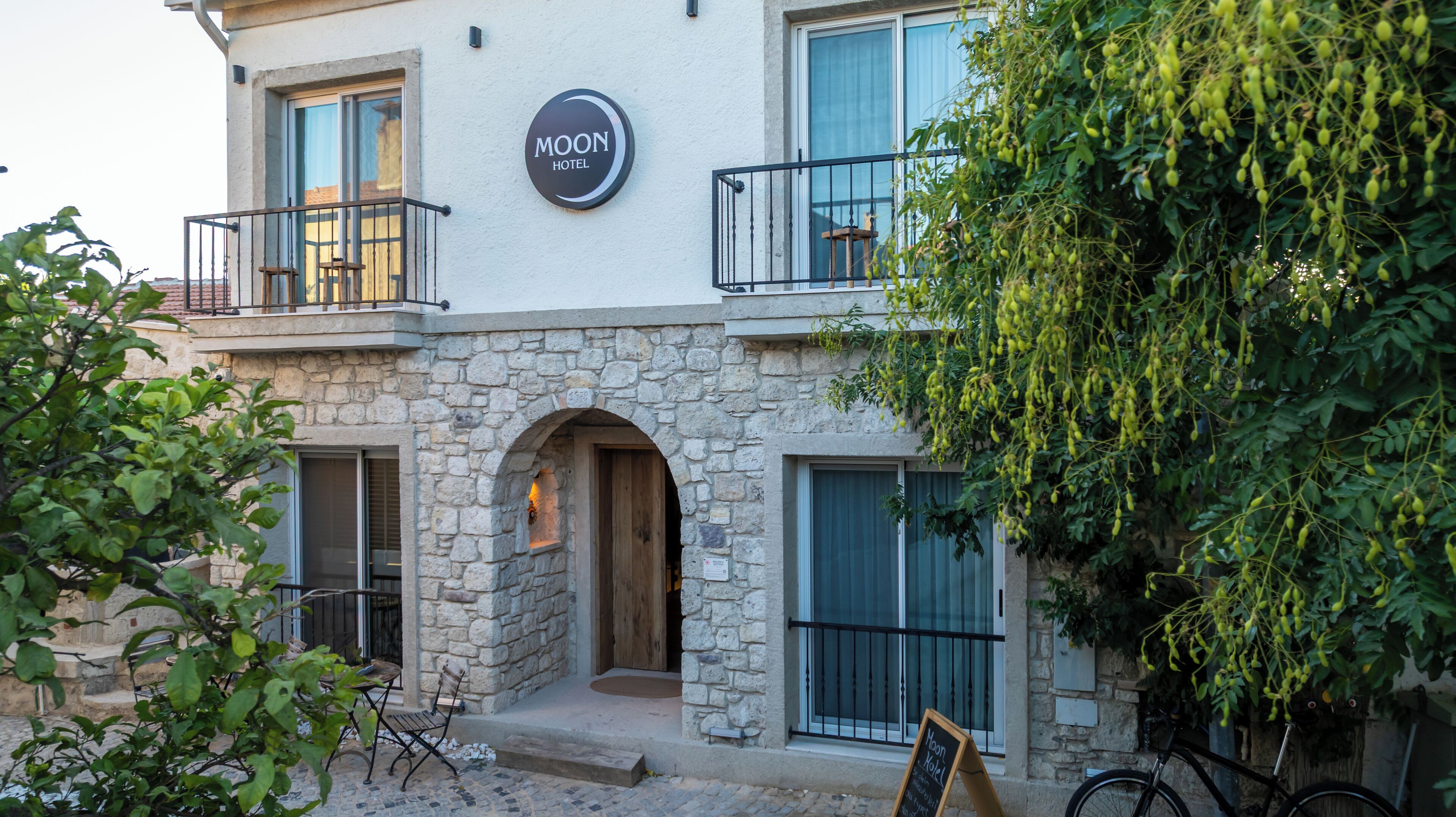 A hotel with a stone facade, a balcony, and a sign reading "MOON HOTEL".