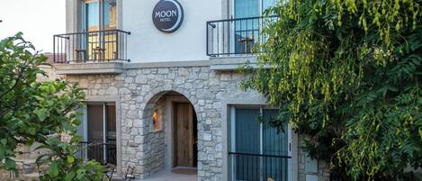 A hotel with a stone facade, a balcony, and a sign reading "MOON HOTEL".