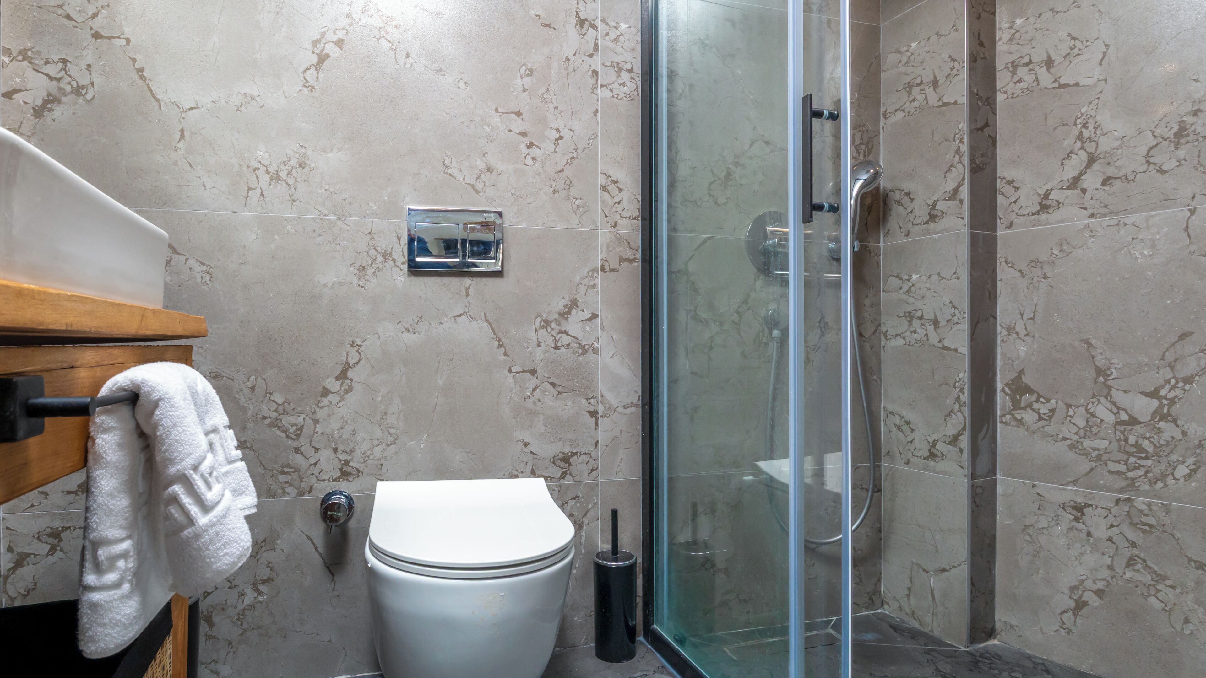 A bathroom with a toilet, a glass shower enclosure, and a towel rack.