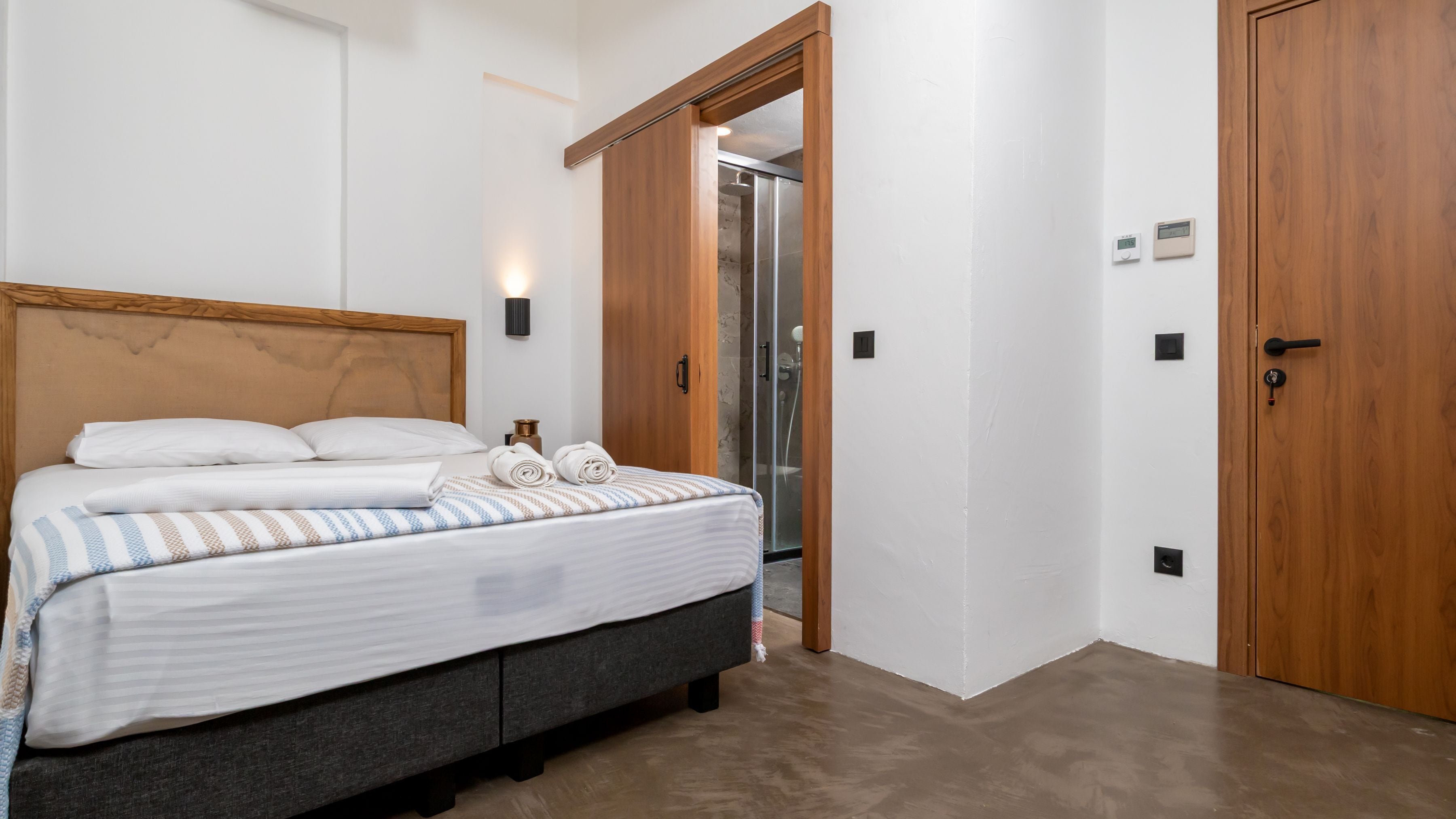 A bedroom with a bed, a wooden door, and a shower area.