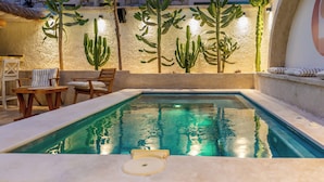 Una piscina con agua cristalina y azul, rodeada de sillas y una mesa de madera.