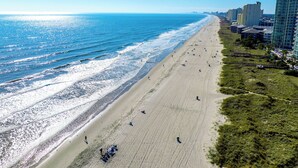 A beach with a clear view of the ocean and a row of buildings along the shore. - The Beach Jewel - 100% Newly Renovated in 2024! (North Myrtle Beach)