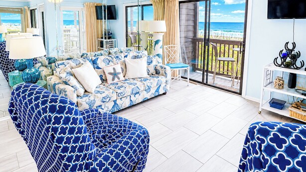 A living room with a sofa, chairs, a TV, and a balcony with a view.