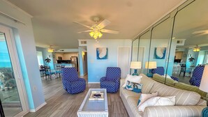 A living room with a sofa, armchairs, a coffee table, and a ceiling fan.