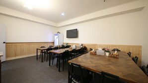 A conference room with a long wooden table, black chairs, a whiteboard, and a flat-screen TV mounted on the wall. - HOTEL HIGHFERE (Changwon)
