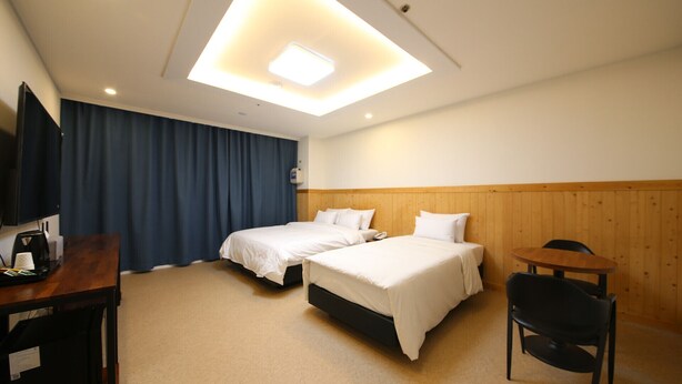 A hotel room with two beds, a desk, a chair, and a television. - HOTEL HIGHFERE (Changwon)
