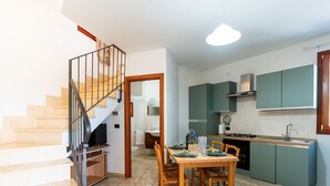 A modern kitchen with green cabinets, a dining area with a wooden table and chairs, and a staircase with a metal railing. - Lovely apartment for 4 people with A/C, WIFI, terrace, pets allowed and panoramic view (Andora)