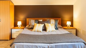 A neatly arranged bedroom with a wooden headboard, two bedside tables with lamps, and a large bed with a grey blanket. - Lovely apartment for 4 people with A/C, WIFI, terrace, pets allowed and panoramic view (Andora)