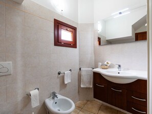 Een badkamer met een wastafel, bidet en handdoekrek.
