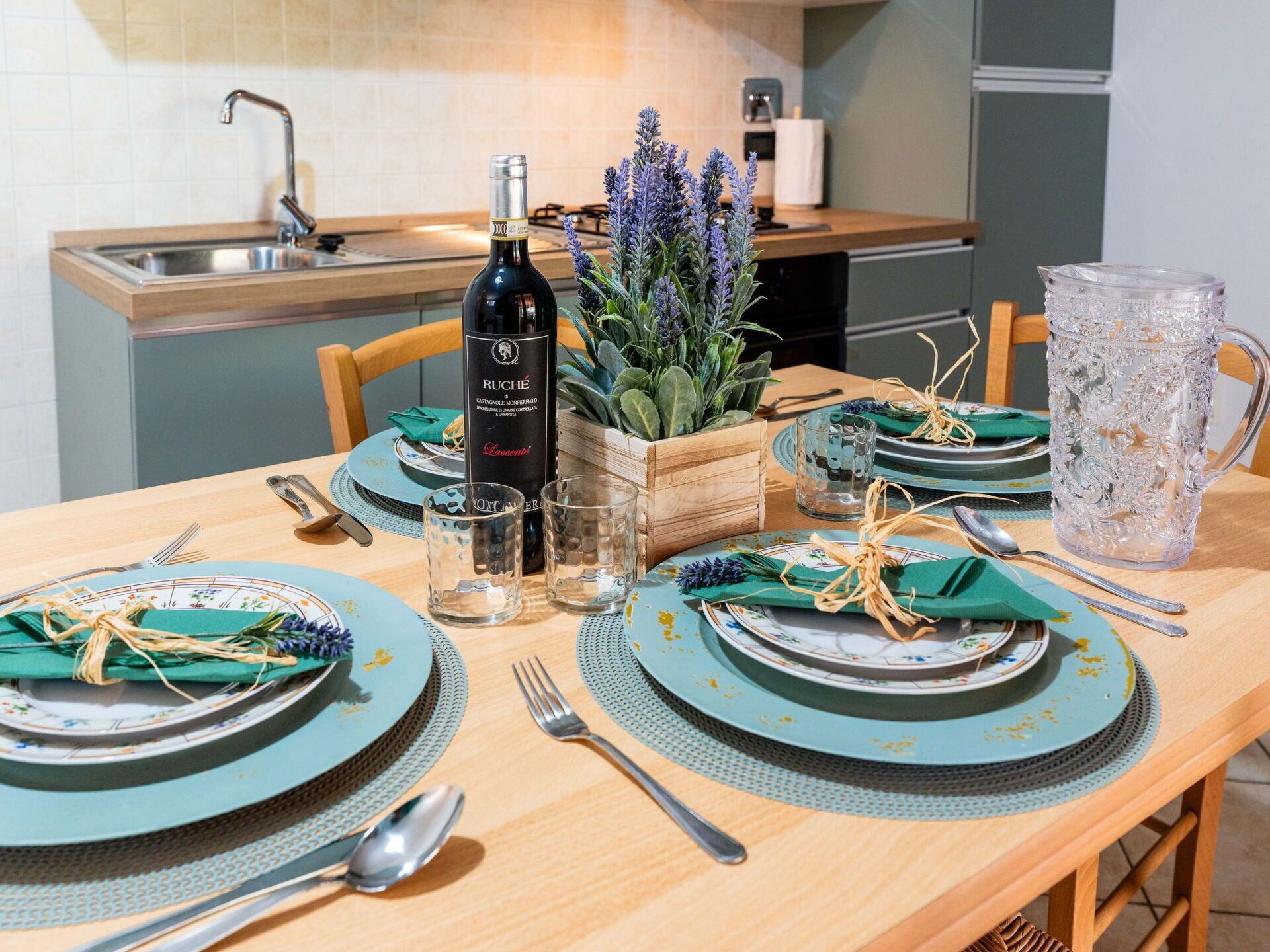 A dining table set with plates, glasses, and cutlery, a bottle of wine, and a decorative plant.