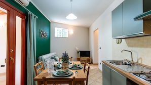 A compact kitchen with a sink, stove, and a dining area with a table set for two. - Cosy apartment for 4 people with WIFI, balcony, pets allowed and panoramic view (Andora)