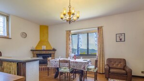 A dining area with a fireplace, a chandelier, and a view of the outdoors.