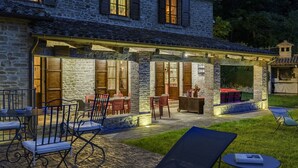 Edificio de piedra con un patio techado que ofrece mobiliario exterior y una piscina pequeña.