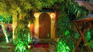 Uma porta de madeira com parede de tijolos e um pequeno alpendre com um tapete vermelho e uma cesta de vime.