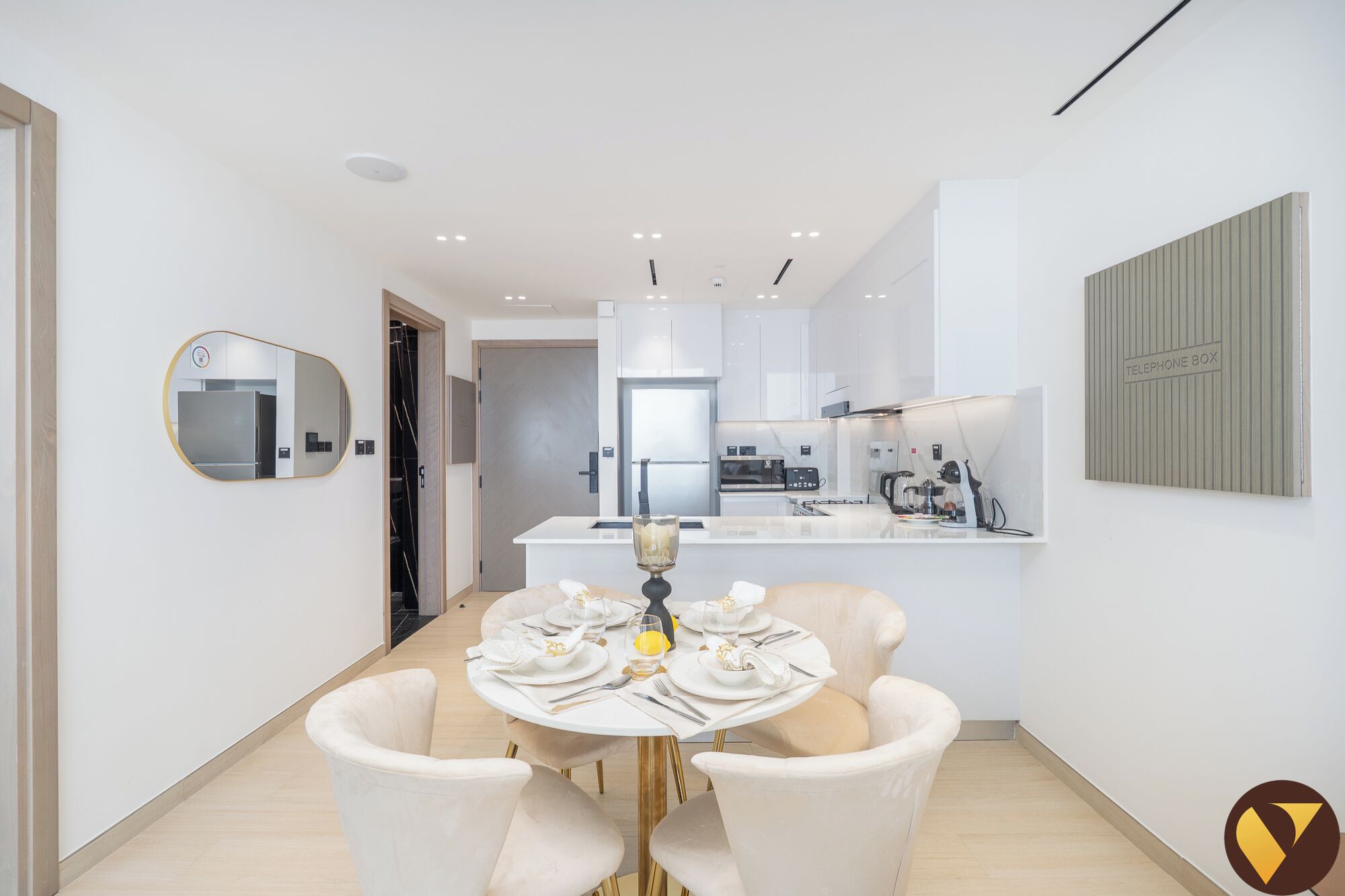 A modern kitchen with white cabinets, a central island, and a dining area with a round table and two chairs.