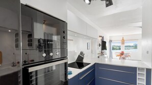 Eine moderne Küche mit einem Bosch-Backofen, einer schwarzen Induktionskochplatte und Blick auf eine Stadtlandschaft durch das Fenster.