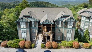 A large, multi-story building with a central entrance, surrounded by lush greenery and mountains in the background. - Peaceful 2/2 with VIEWS: Echota (Banner Elk)