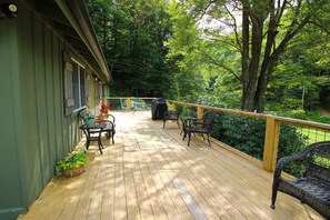 Eine Holzterrasse mit Gartenmöbeln, umgeben von viel Grün.