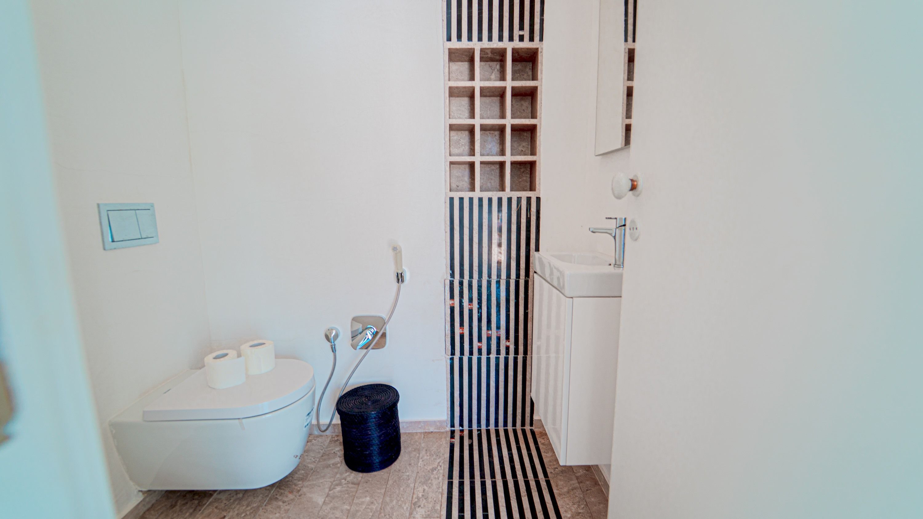 A small, modern bathroom with a toilet, a sink, and a shower.