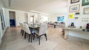 A spacious dining area with a large table and chairs, a kitchen area with a counter, and a living room with a sofa and coffee table.