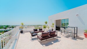 Una terraza en la azotea con un conjunto de sofás, sillas y una zona de comedor.
