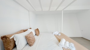 A minimalist hotel room with a bed, pillows, and neatly folded towels. - Padel Resort Villa Romana 2bdrs (Raf Raf)