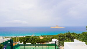 A coastal view with a beach, a tennis court, and a distant island. - Padel Resort Villa Romana 2bdrs (Raf Raf)