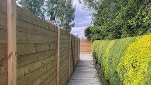 A wooden fence with a concrete pathway leading to a gate. - 1-bed Cosy Cottage Near Emerald Park - Sleeps 5 (Rackenstown)