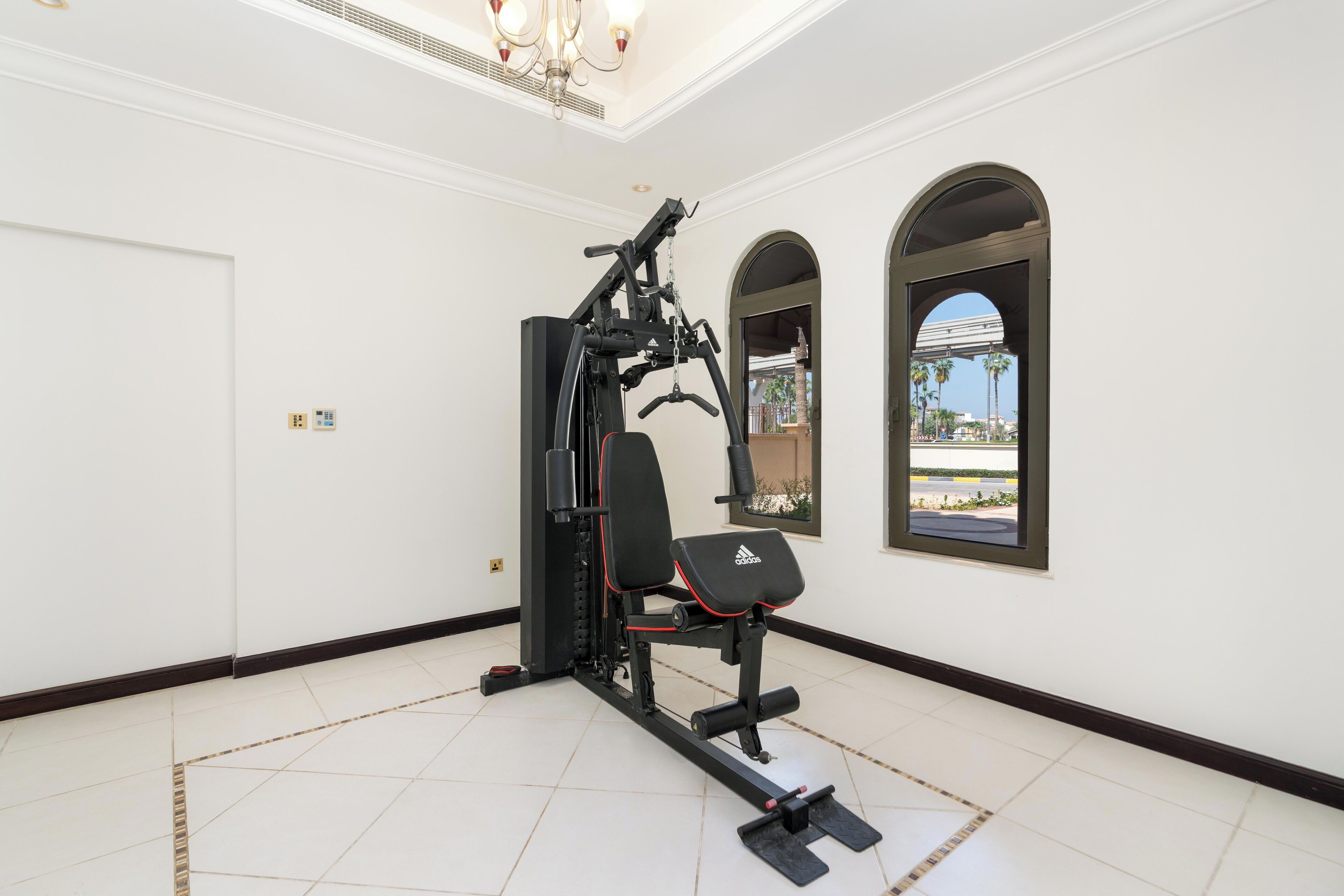 Un gimnasio con bicicleta estática, banco de pesas y pesas sueltas.