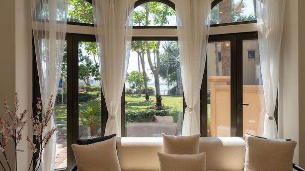 Ein Zimmer mit einer Couch und Blick auf einen Garten durch große Fenster.