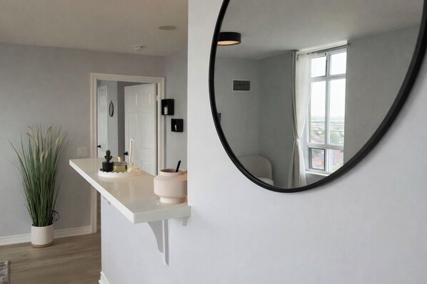 A bathroom with a white vanity, a round mirror, and a potted plant. - Premium 2BR Extended Stay Near YYZ Free Parking Included (Toronto)