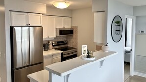 A modern kitchen with white cabinets, stainless steel appliances, and a white countertop. - Premium 2BR Extended Stay Near YYZ Free Parking Included (Toronto)