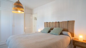 Une chambre à coucher avec un lit, une table de chevet avec une lampe et un luminaire suspendu.