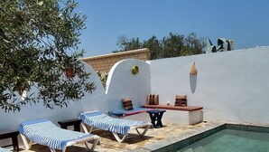 A poolside area with lounge chairs and a stone-tiled floor. - Welcome to Studio Jasmin in this corner of paradise in Menzel Soltane Ahmed (MIDOUN)
