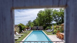 Ein rechteckiger Swimmingpool mit einer Steinmauer und Grünpflanzen im Hintergrund.