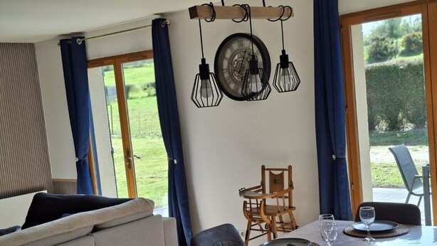Een eetruimte met een tafel voor vier personen, een klok aan de muur en uitzicht op het omliggende landschap.