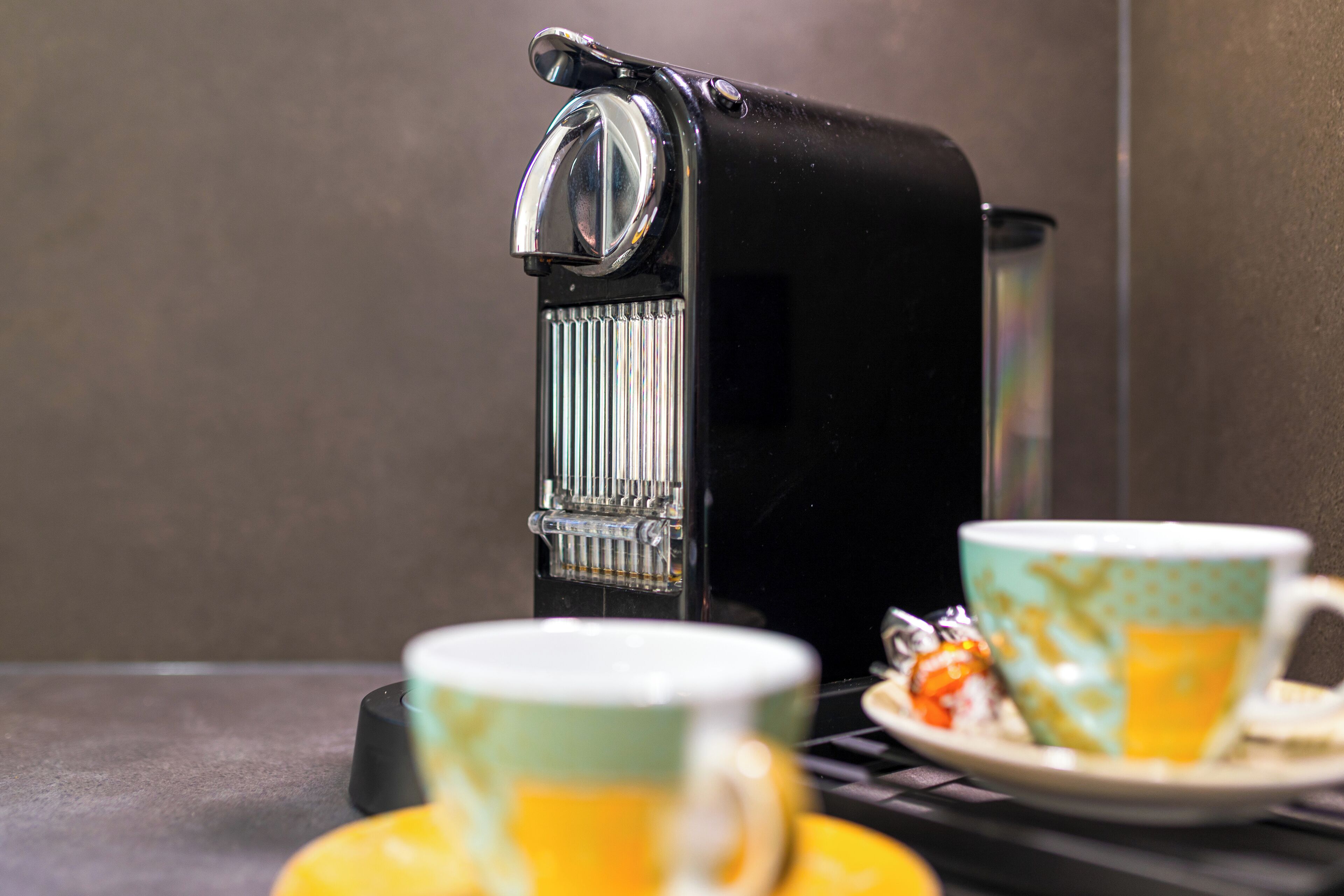 A coffee maker with two cups on a tray.