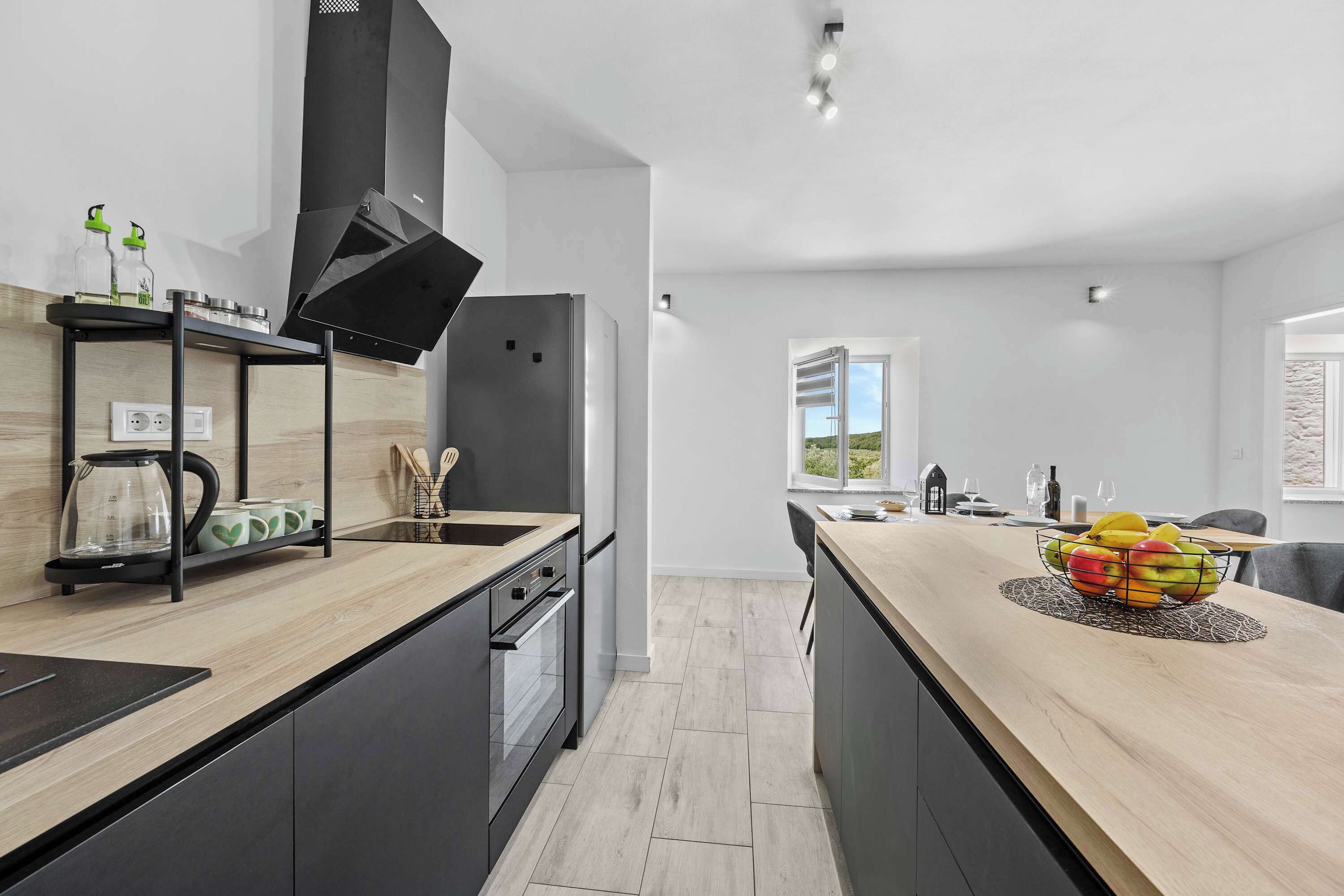 Una cocina moderna con una isla central, horno empotrado y campana extractora negra.