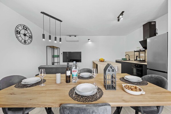 A modern dining area with a wooden table, chairs, and a decorative wall clock.